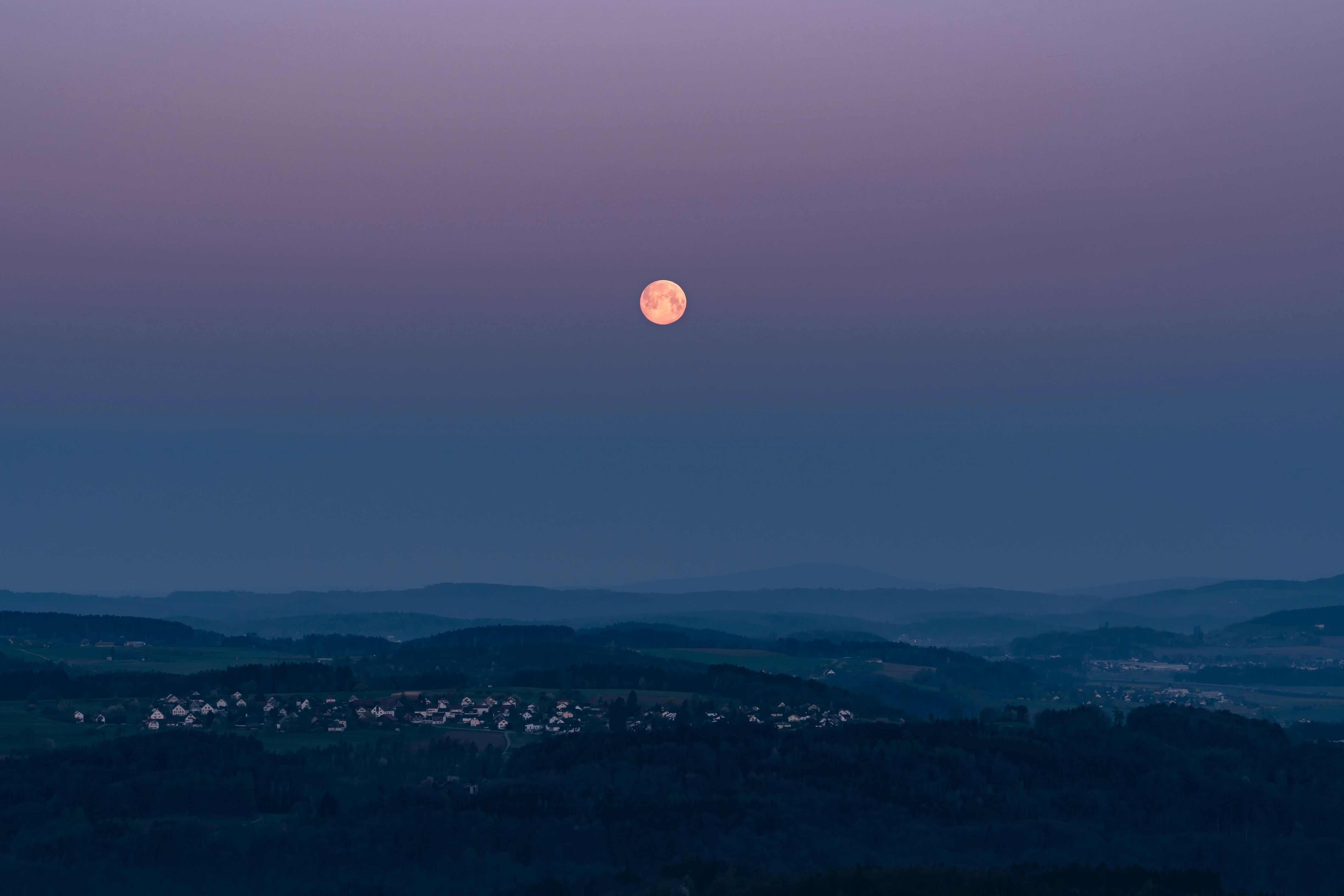 Blue hour landscape with cool blue tones and pink moon showing ethereal twilight lighting after sunset